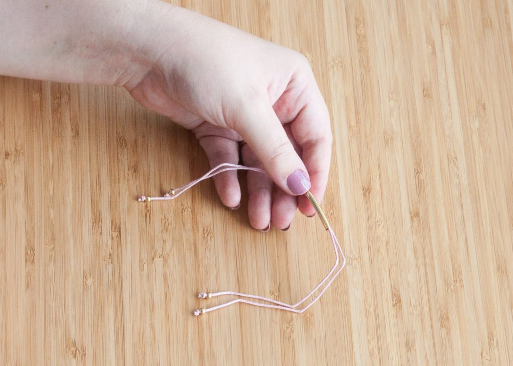 3 Easy DIY Bracelets You'll Actually Want to Wear. Image Description: A hand holding a beaded bracelet.